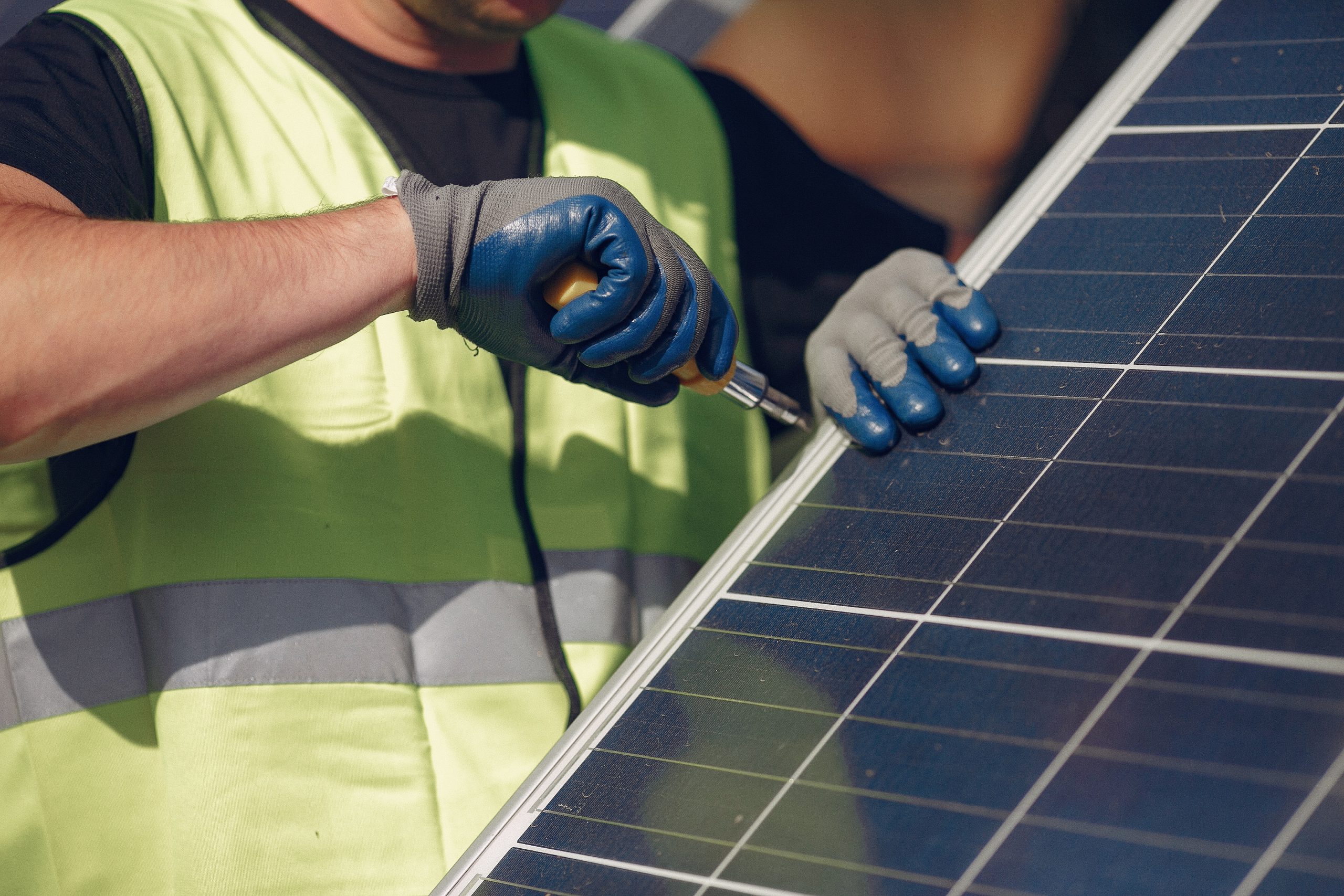 Man in a white helmet near a solar panel